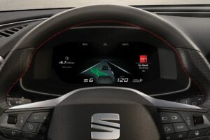 Närbild på bilens digitala instrumentbräda som visar hastighet och musikuppspelning.