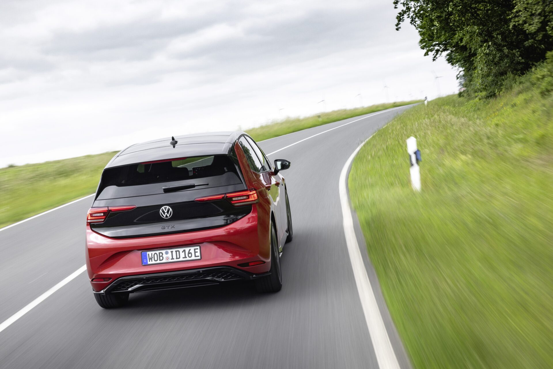 Baksidan av en röd Volkswagen elbil som kör på en kurvig landsväg.