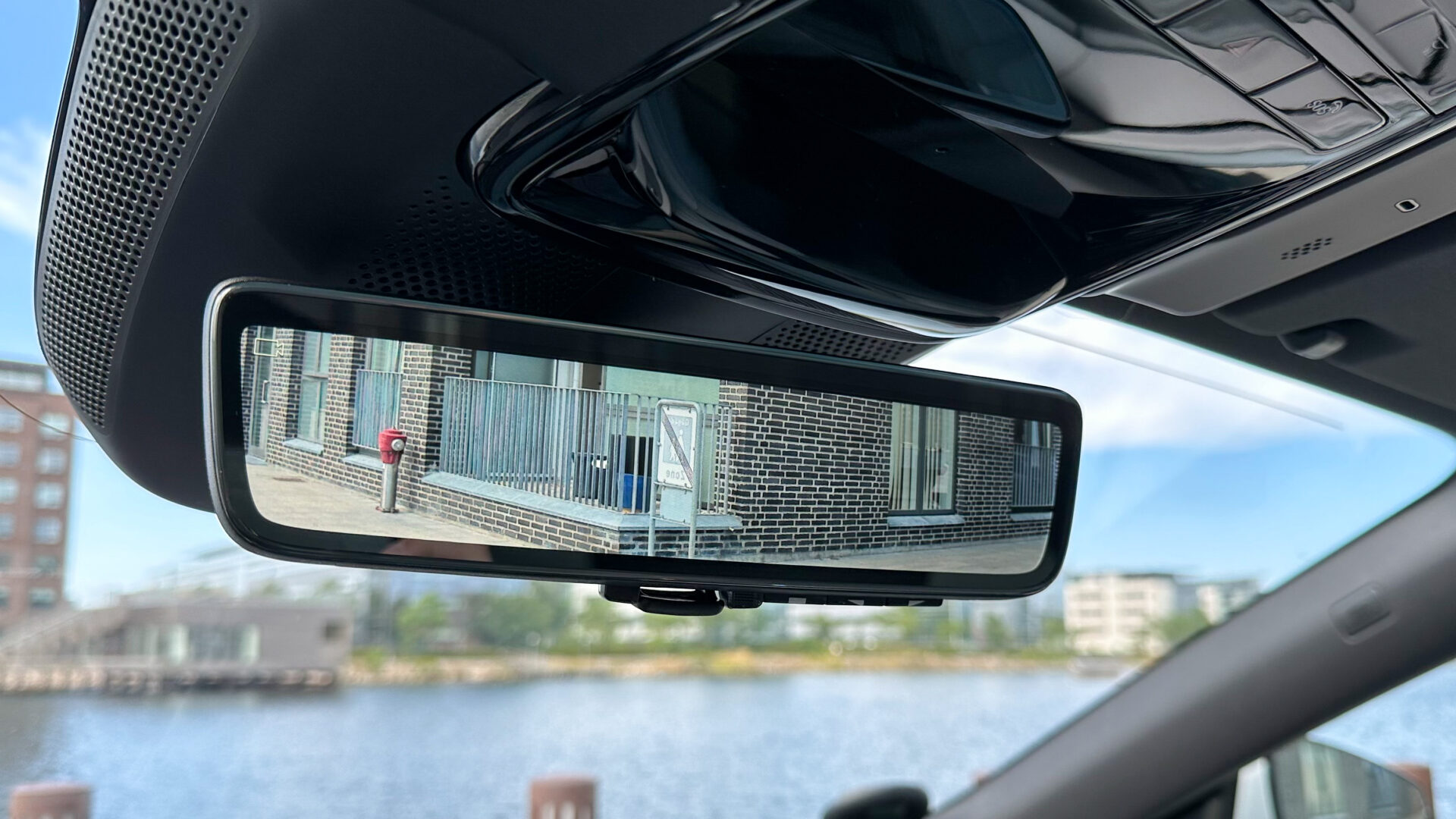 Bakspegeln som visar reflektionen av en trottoar och en byggnad.