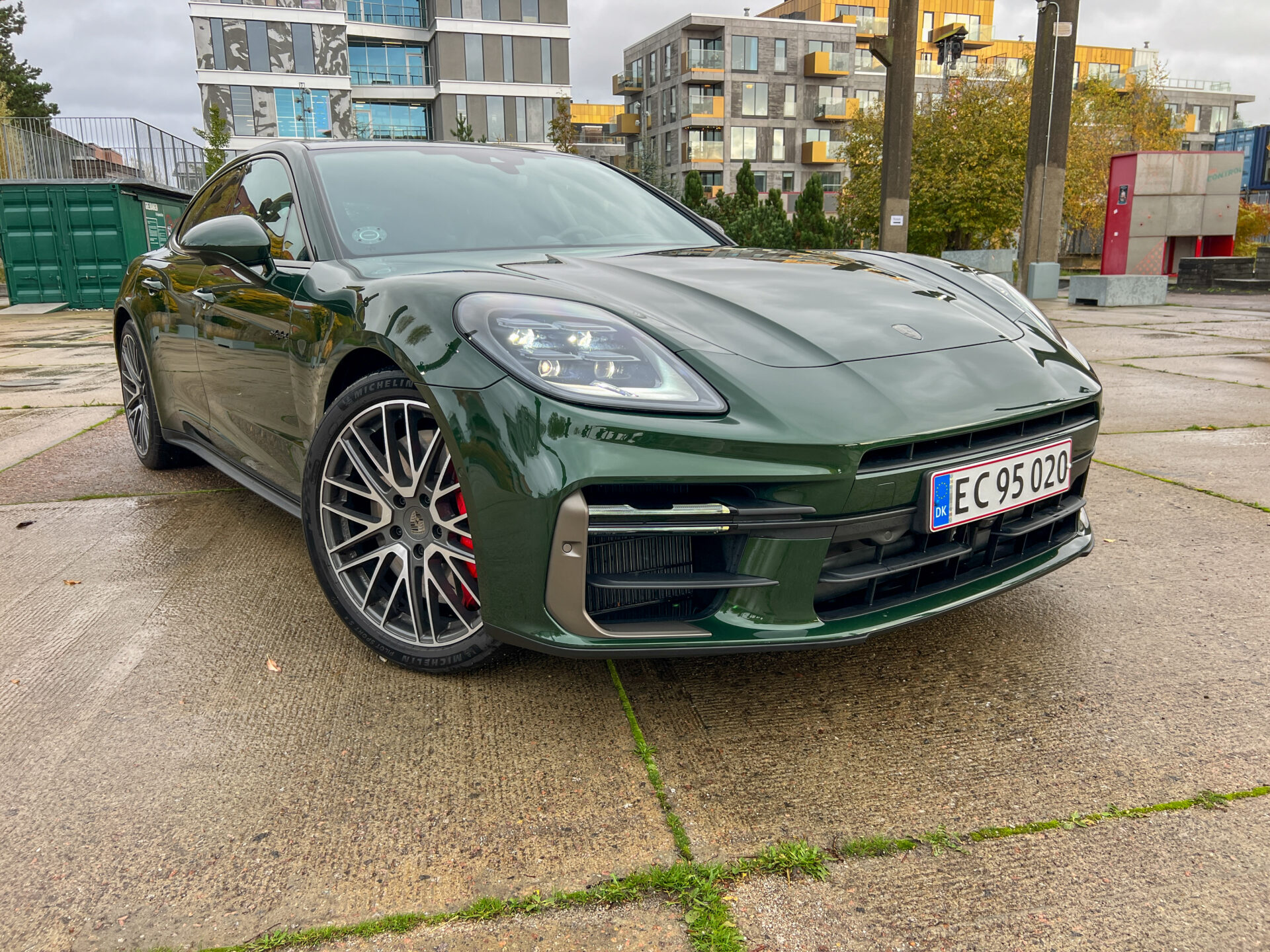 Grön Porsche Panamera framifrån snett, parkerad på betongplattor.