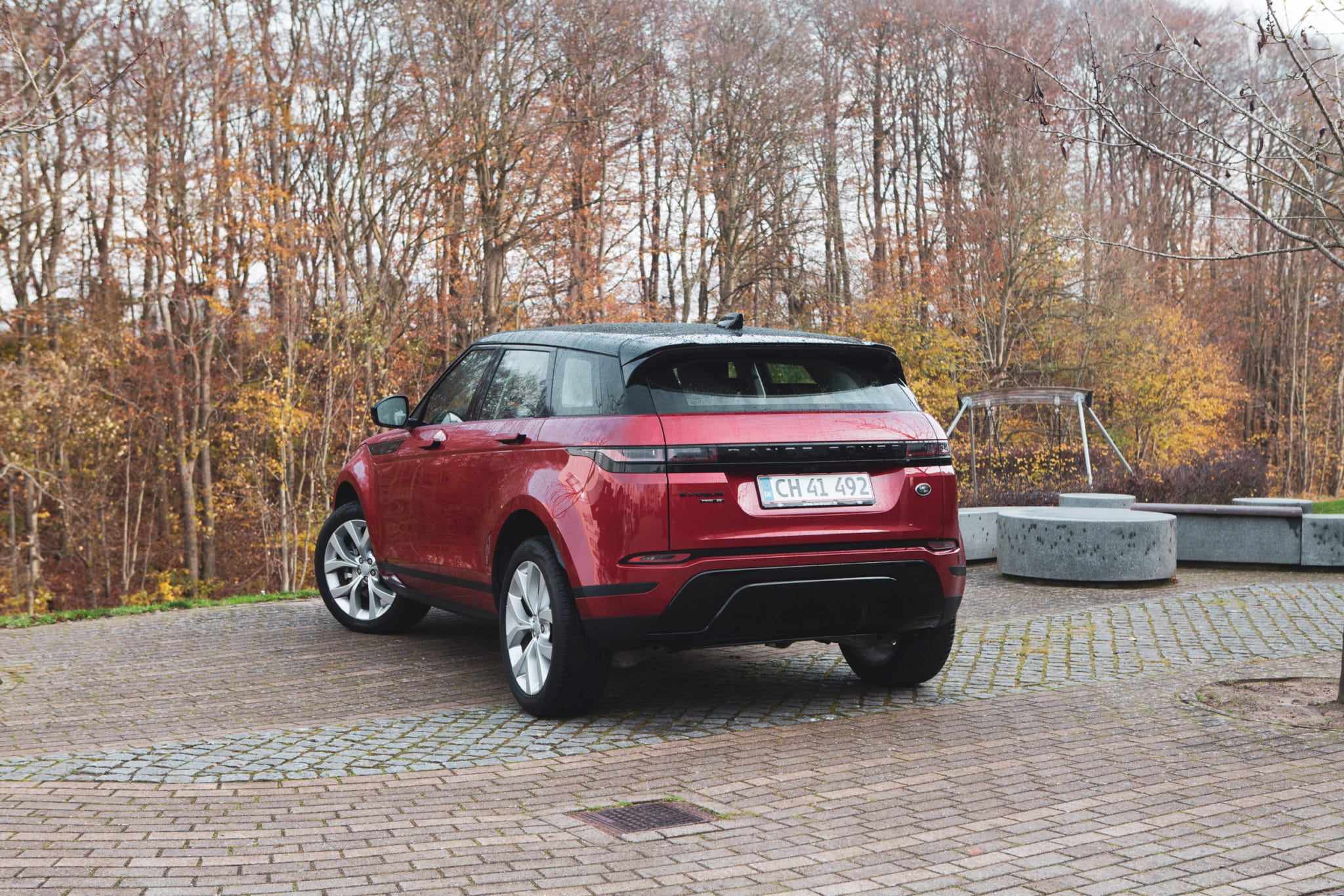 Röd range rover evoque parkerad vid skog