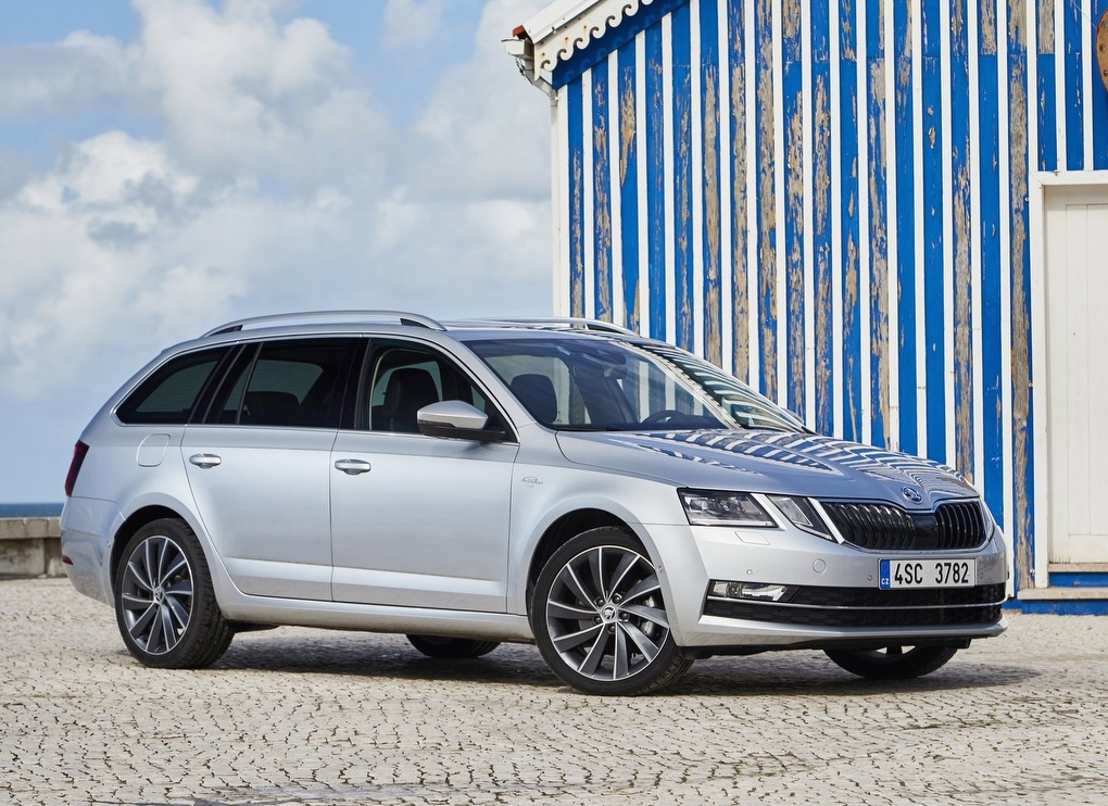 Silverfrägad Skoda Octavia parkerad vid industribyggnad.